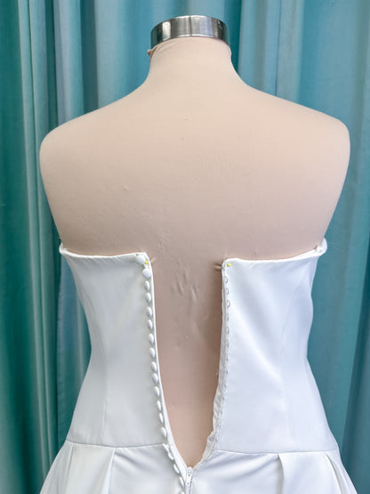 Morilee 15080 Tiana A-line wedding dress in satin with cowl-draped strapless neckline, drop waist, contoured seaming, pleated skirt, and covered buttons to hem.