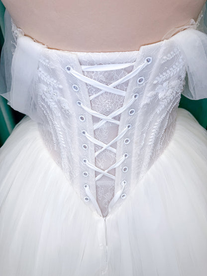 Morilee 1010036 Virtuoso ballgown wedding dress on mannequin with scoop neckline, off-the-shoulder tulle sleeves, beaded bodice, and lace-up corset back