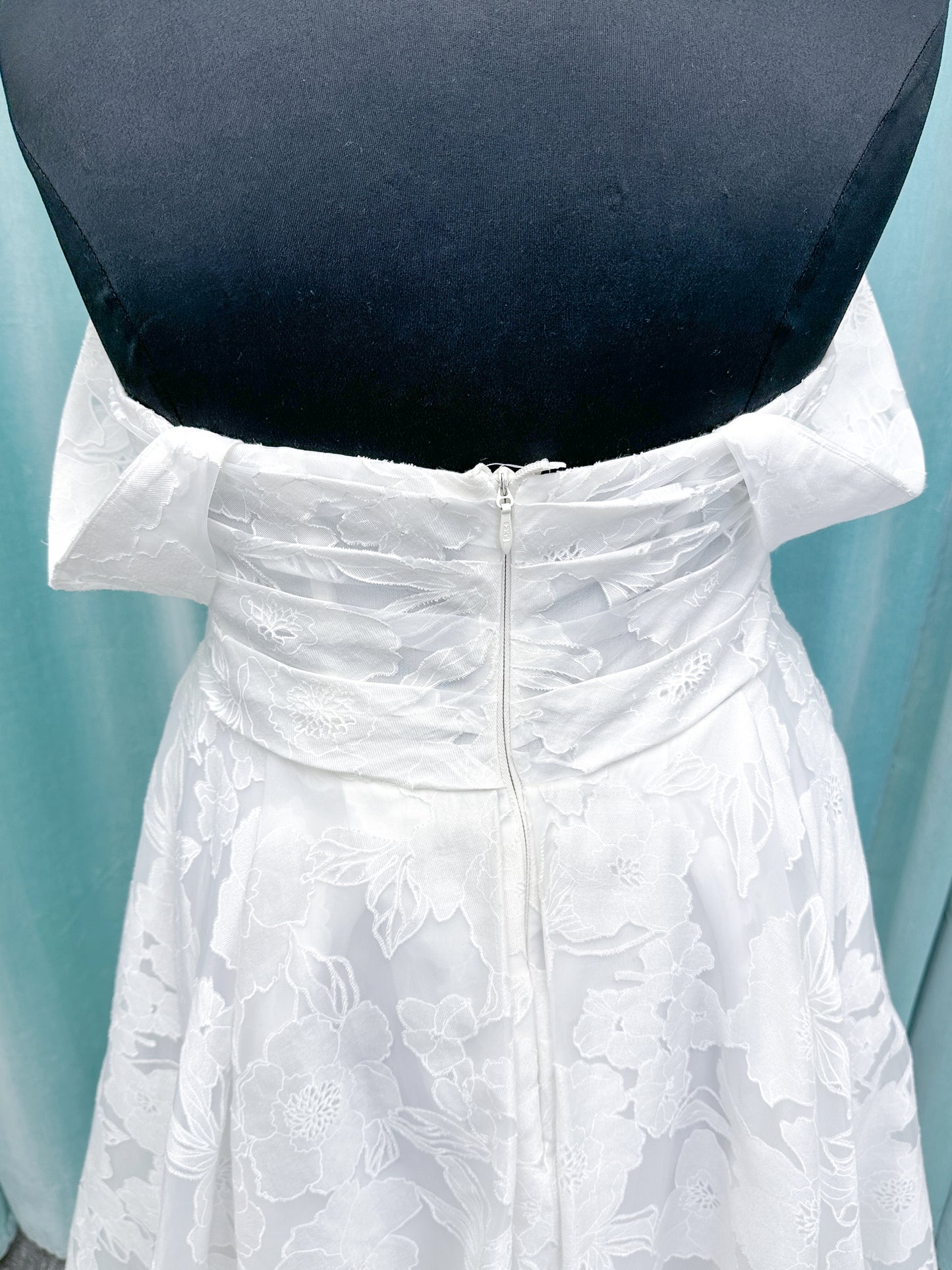Willow ivory off-the-shoulder floral jacquard A-line wedding dress on mannequin with full skirt and front slit.
