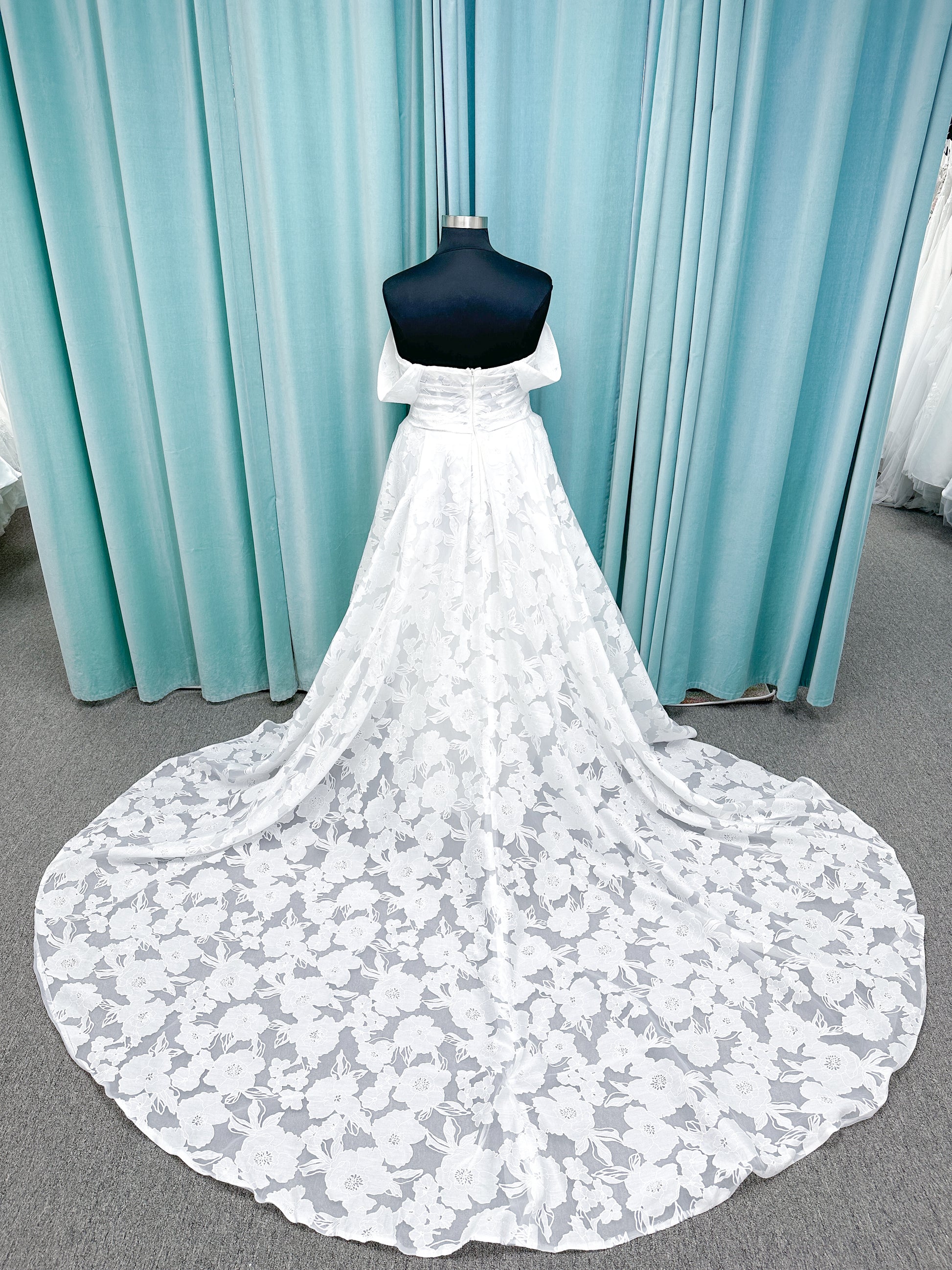 Willow ivory off-the-shoulder floral jacquard A-line wedding dress on mannequin with full skirt and front slit.
