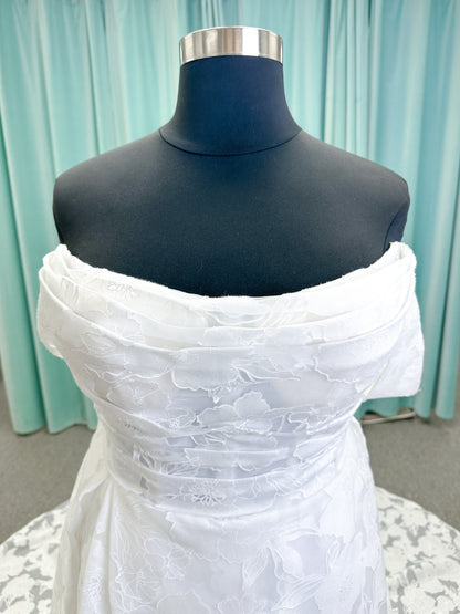 Willow ivory off-the-shoulder floral jacquard A-line wedding dress on mannequin with full skirt and front slit.
