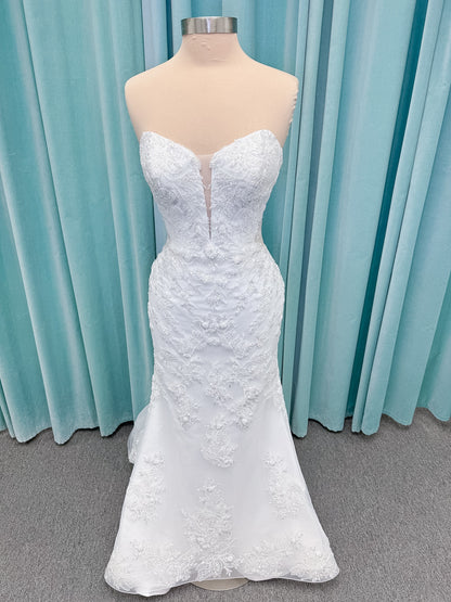 Moonlight Bridal J6996 Zira mermaid wedding dress on mannequin with strapless pointed sweetheart illusion neckline, side bodice cutouts, beaded lace appliques on shimmer net, drop waist, and chapel train with horsehair trim