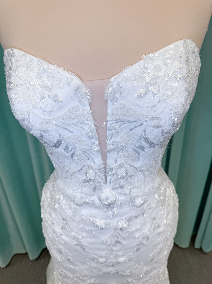 Moonlight Bridal J6996 Zira mermaid wedding dress on mannequin with strapless pointed sweetheart illusion neckline, side bodice cutouts, beaded lace appliques on shimmer net, drop waist, and chapel train with horsehair trim