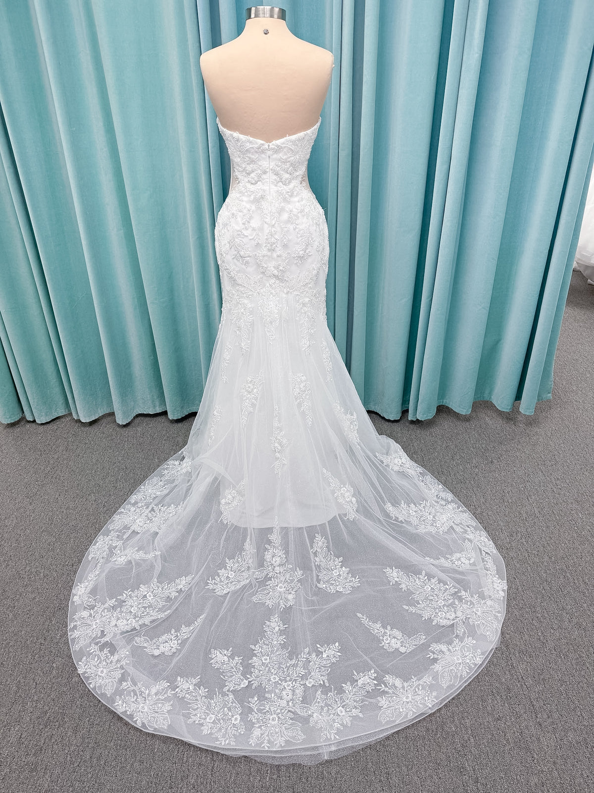 Moonlight Bridal J6996 Zira mermaid wedding dress on mannequin with strapless pointed sweetheart illusion neckline, side bodice cutouts, beaded lace appliques on shimmer net, drop waist, and chapel train with horsehair trim
