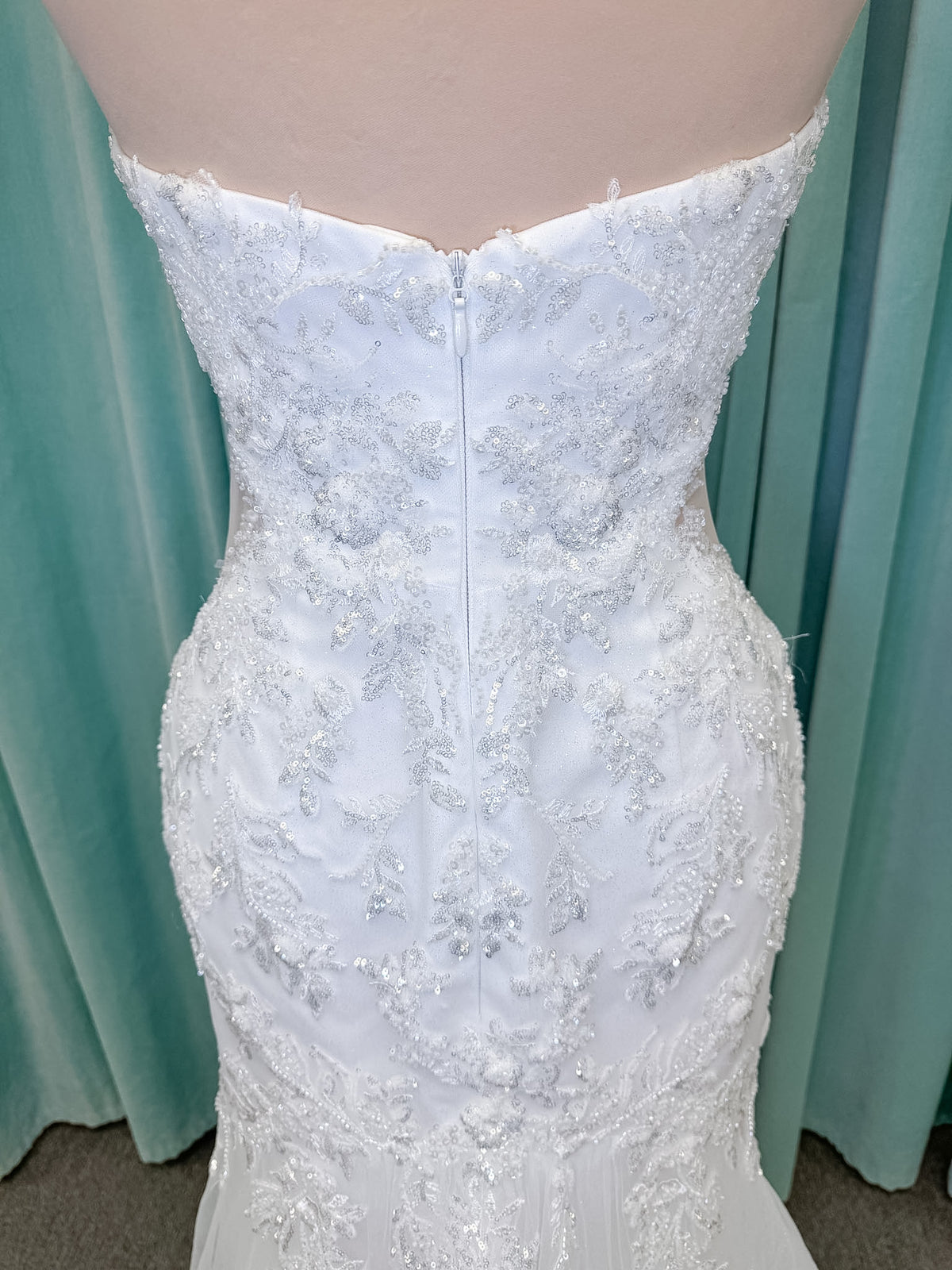 Moonlight Bridal J6996 Zira mermaid wedding dress on mannequin with strapless pointed sweetheart illusion neckline, side bodice cutouts, beaded lace appliques on shimmer net, drop waist, and chapel train with horsehair trim