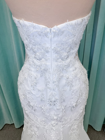 Moonlight Bridal J6996 Zira mermaid wedding dress on mannequin with strapless pointed sweetheart illusion neckline, side bodice cutouts, beaded lace appliques on shimmer net, drop waist, and chapel train with horsehair trim