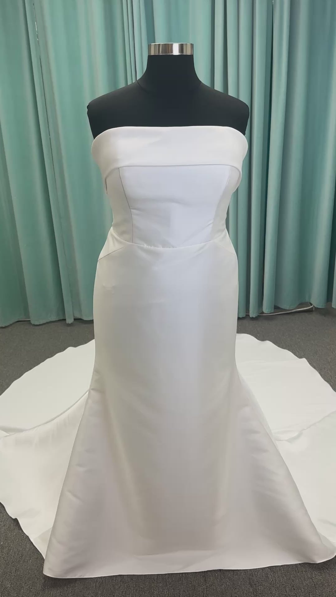 Oh Darling ivory strapless satin sheath wedding dress on mannequin with bandeau neckline, oversized statement bow at the waist, and voluminous overskirt.
