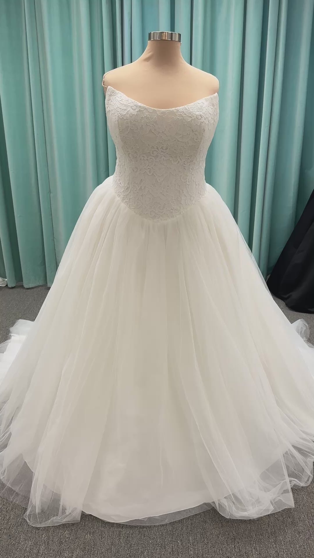 Plus size strapless lace ballgown wedding dress with cat-eye neckline, basque waist, full tulle skirt, and detachable satin bow by Stella York Style SY8189