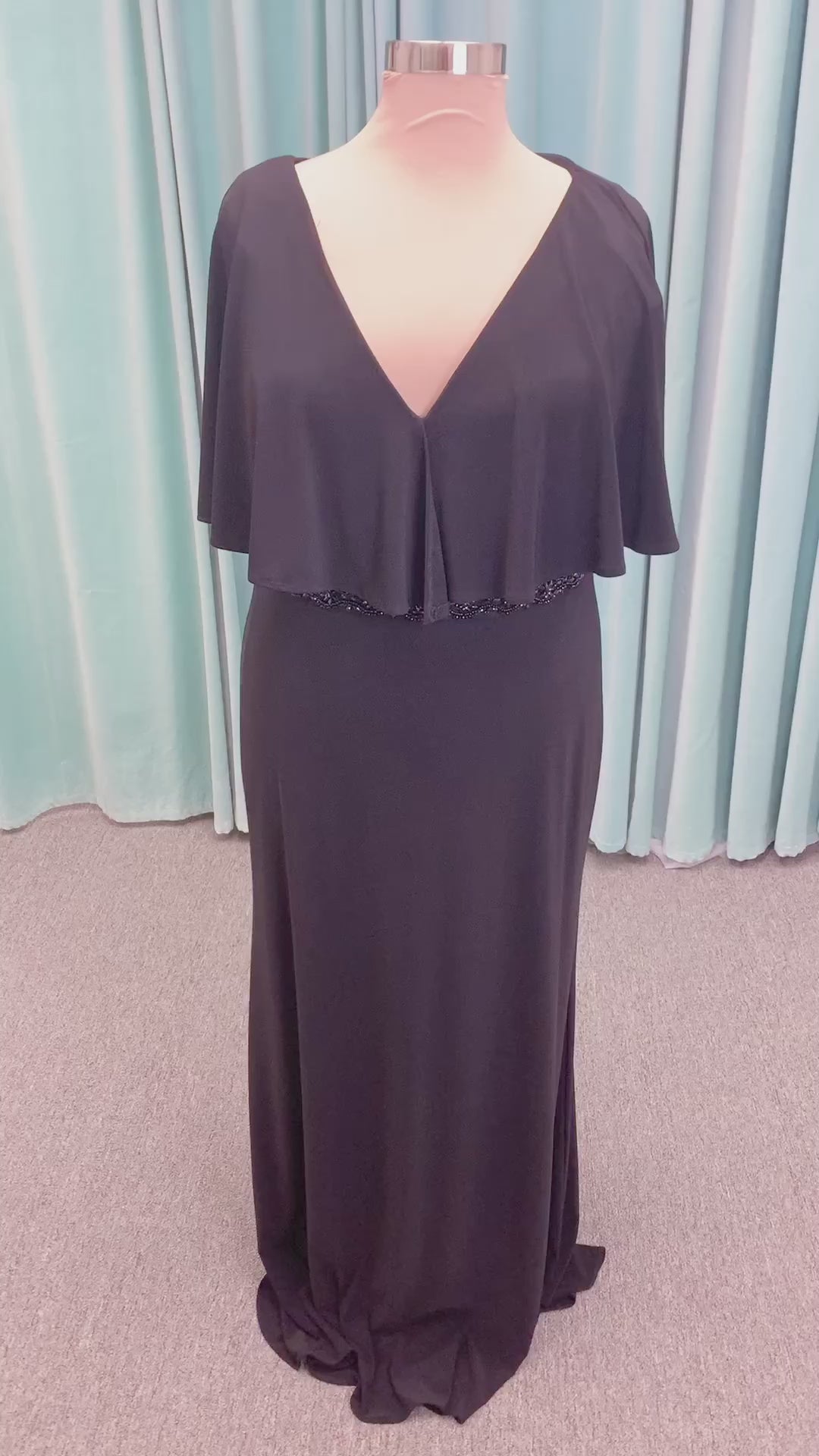 Morilee MLNY 73124 sheath mother of the bride dress on mannequin with V-neckline, flowing capelet overlay, crystal beaded waistband, and slim jersey sheath skirt