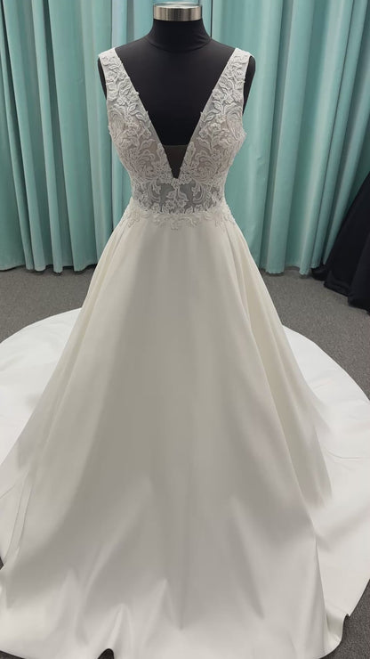 Satin A-line wedding dress with deep V-neckline, lace bodice, illusion tulle inset, and flowing skirt with pockets and long train
