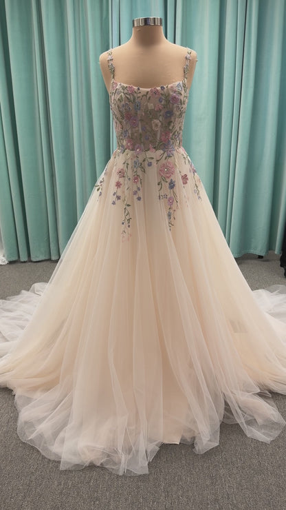 Stella York 8063 ivory and pastel colorful embroidered lace A-line wedding dress on mannequin with floral spaghetti straps, scoop neckline, and soft tulle skirt.
