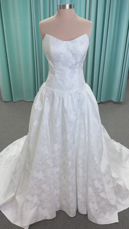 Moonlight Bridal J6994 Marama ballgown wedding dress on mannequin with strapless scoop neckline, textured satin jacquard, fitted drop-waist bodice, detachable short bow sleeves, full skirt, and sweep train