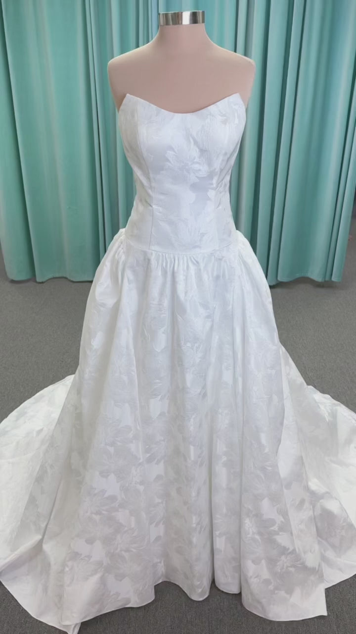 Moonlight Bridal J6994 Marama ballgown wedding dress on mannequin with strapless scoop neckline, textured satin jacquard, fitted drop-waist bodice, detachable short bow sleeves, full skirt, and sweep train