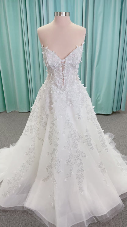 Randy Fenoli Goddess ballgown wedding dress on mannequin with plunging sweetheart neckline, 3D leaf appliqué, basque waist, high skirt slit, and sparkle tulle skirt