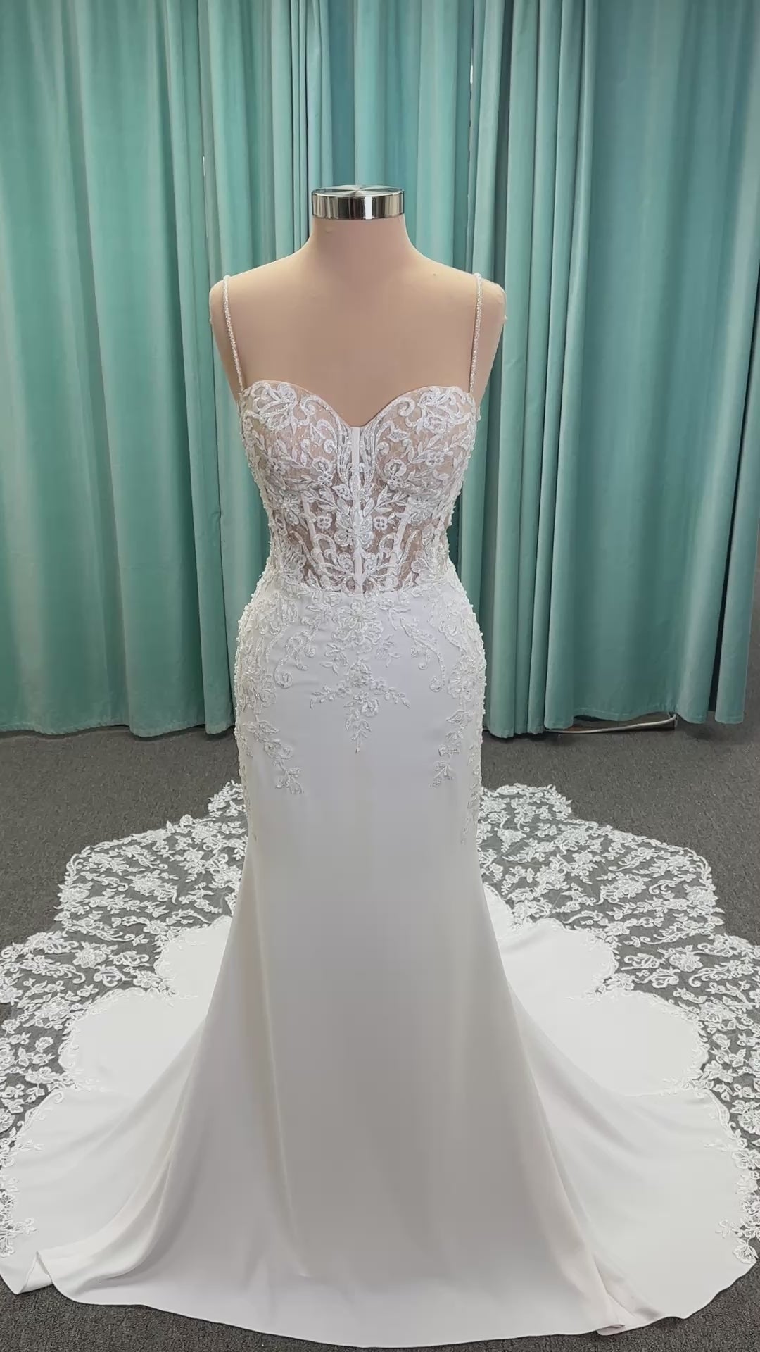 Liena ivory spaghetti strap wedding dress on mannequin with illusion corset bodice, floral lace appliqués, sweetheart neckline, and crepe skirt.
