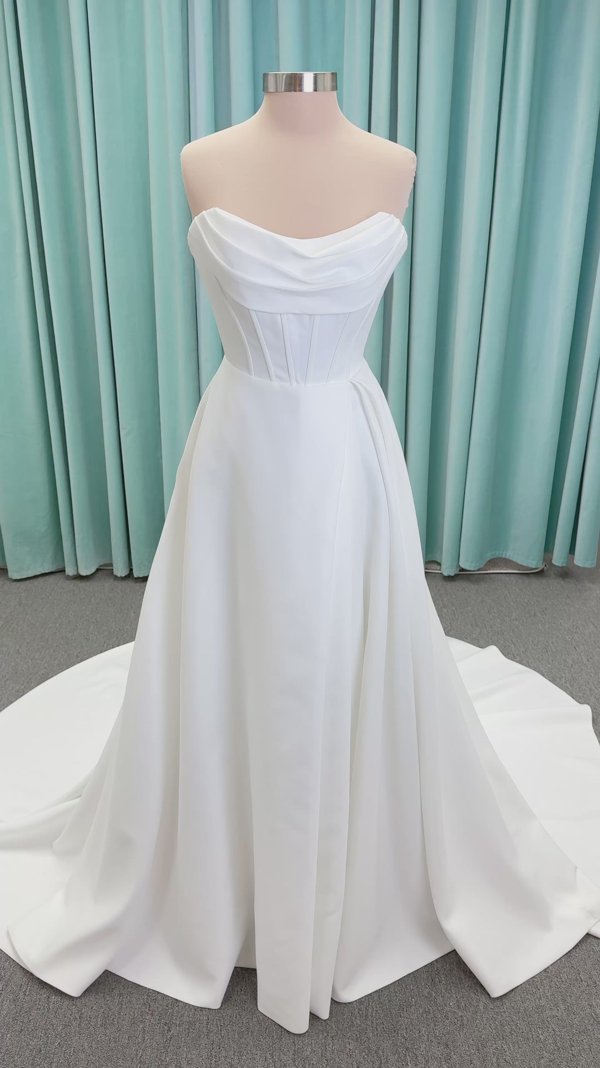 Morilee 15054 Pippa A-line wedding dress on mannequin with cowl neckline, corset bodice, petal satin skirt slit, and pockets