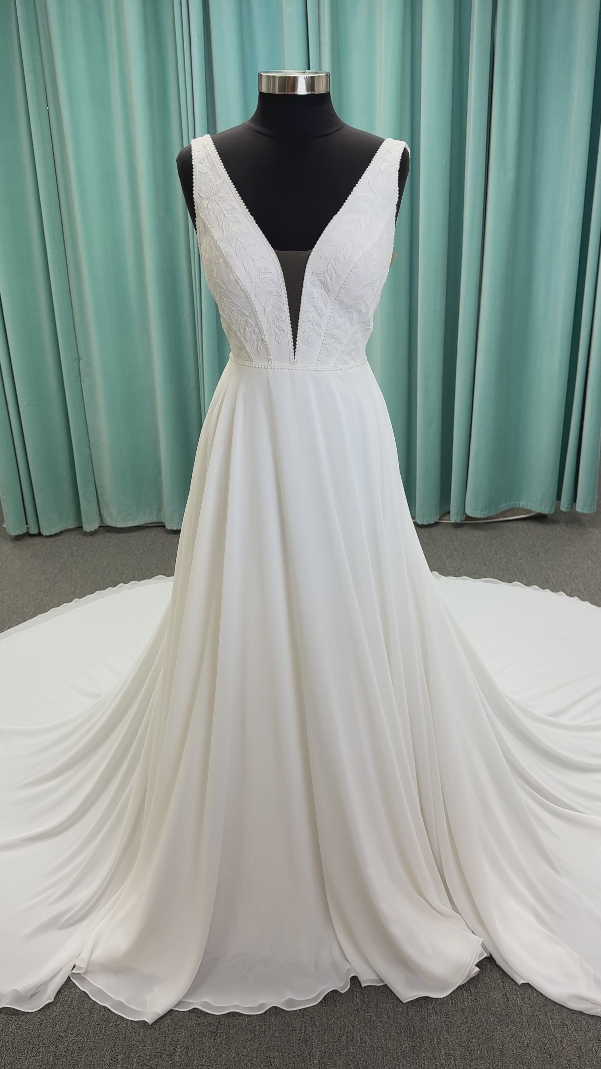 Martha My Dear ivory sleeveless V-neck A-line wedding dress on mannequin with geometric lace bodice panel and flowing chiffon skirt.
