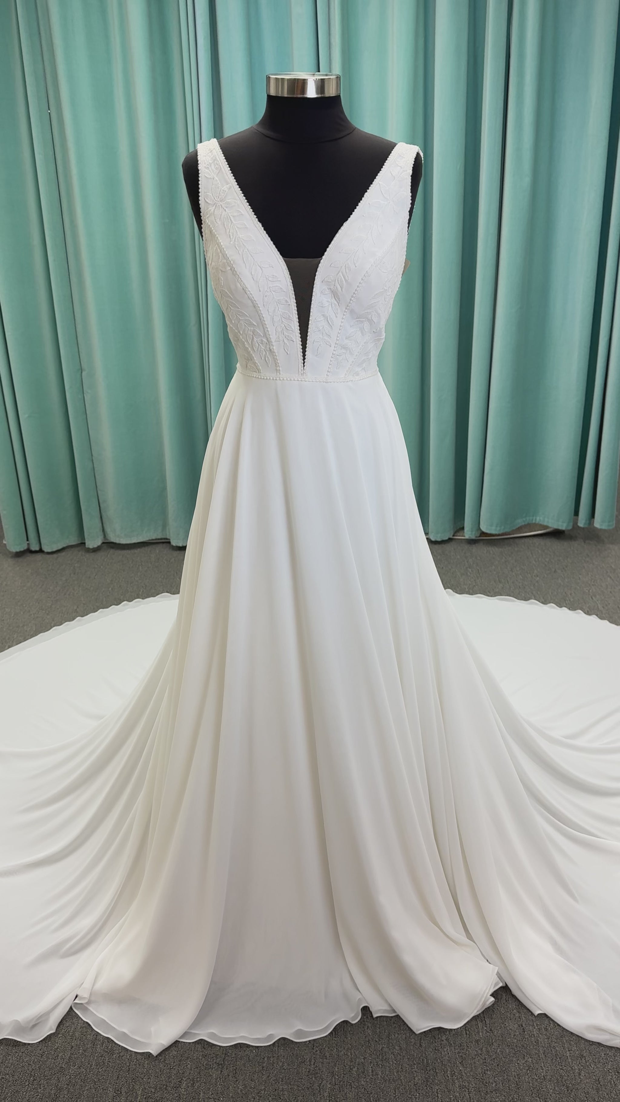 Martha My Dear ivory sleeveless V-neck A-line wedding dress on mannequin with geometric lace bodice panel and flowing chiffon skirt.

