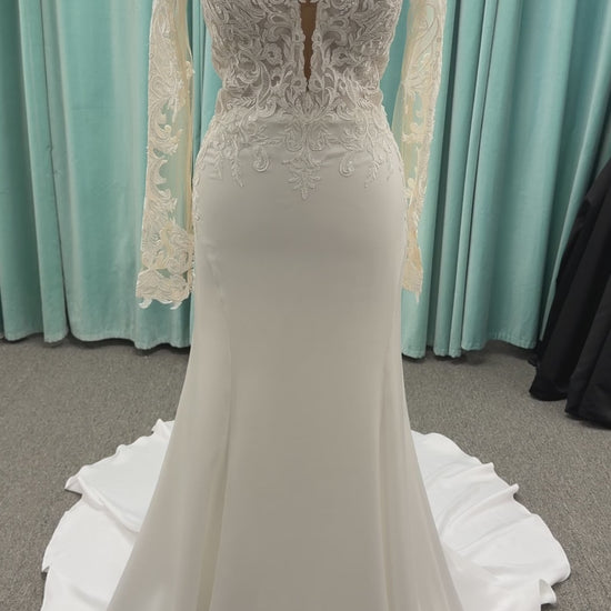 Stella York 8028 ivory lace fit-and-flare wedding dress on mannequin featuring high illusion neckline, sheer long lace sleeves, plunging bodice, and low open back.
