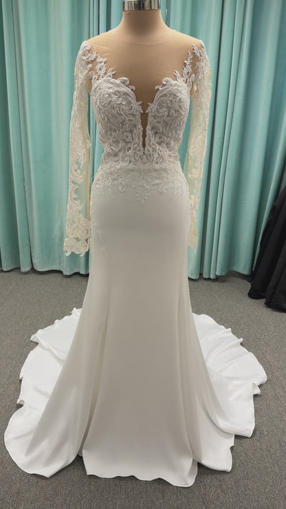 Stella York 8028 ivory lace fit-and-flare wedding dress on mannequin featuring high illusion neckline, sheer long lace sleeves, plunging bodice, and low open back.

