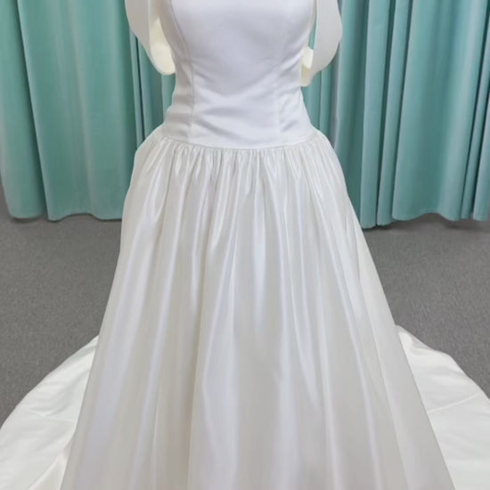Moonlight Bridal J6956 Mahina ballgown wedding dress on mannequin with scoop neckline, detachable off-the-shoulder swag sleeves, drop waist, ruched shimmering satin skirt, and chapel train with horsehair hem