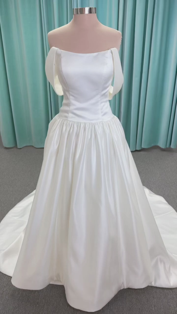 Moonlight Bridal J6956 Mahina ballgown wedding dress on mannequin with scoop neckline, detachable off-the-shoulder swag sleeves, drop waist, ruched shimmering satin skirt, and chapel train with horsehair hem