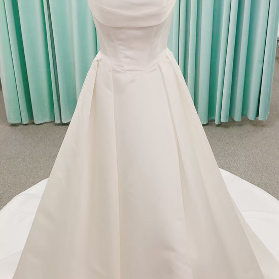 Stella York SY8084 ballgown wedding dress on mannequin with strapless ruched neckline, basque waist bodice, pleated satin skirt, and row of fabric-covered buttons