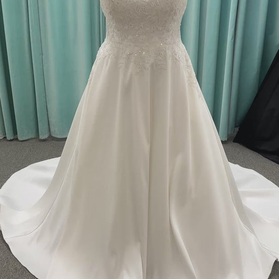 Plus size Stella York 7897 wedding dress in Mikado fabric with square neckline, lace bodice, side cutouts, and flowing A-line skirt with pockets