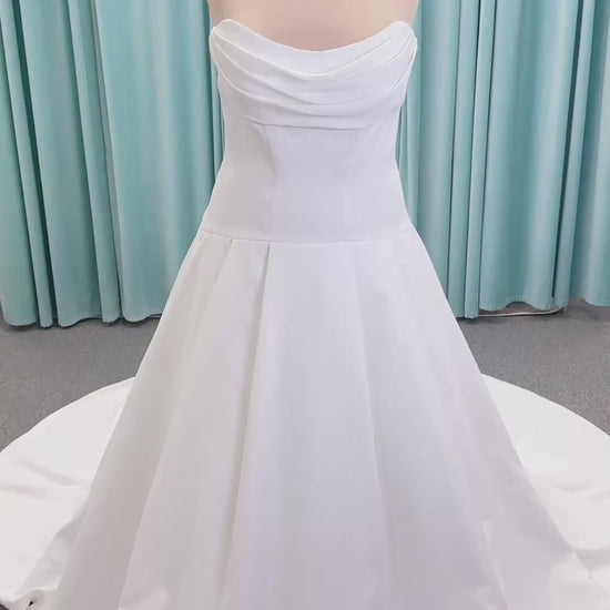 Morilee 15080 Tiana A-line wedding dress in satin with cowl-draped strapless neckline, drop waist, contoured seaming, pleated skirt, and covered buttons to hem.