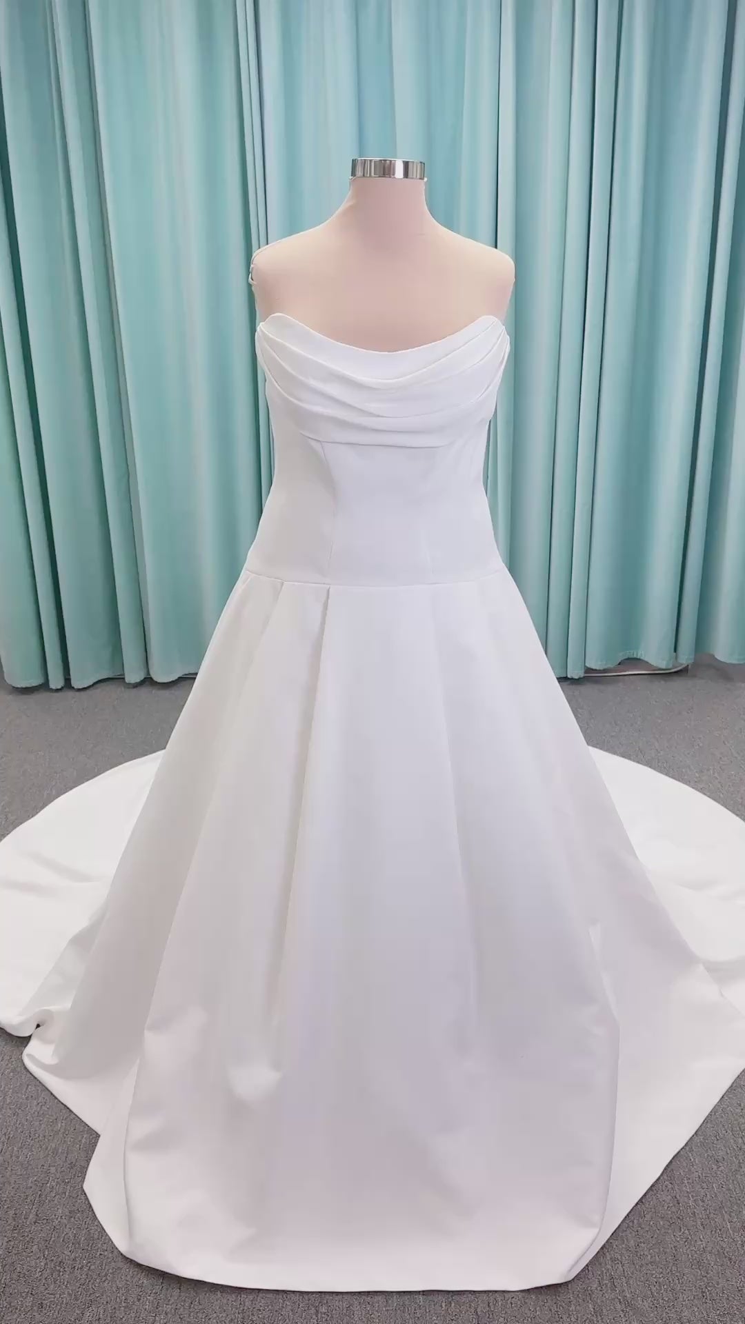 Morilee 15080 Tiana A-line wedding dress in satin with cowl-draped strapless neckline, drop waist, contoured seaming, pleated skirt, and covered buttons to hem.