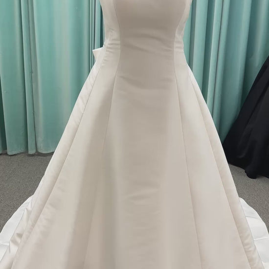 Minimalist Mikado A-line wedding dress with square neckline, clean seams, subtle side cutouts, and detachable oversized bow at the back