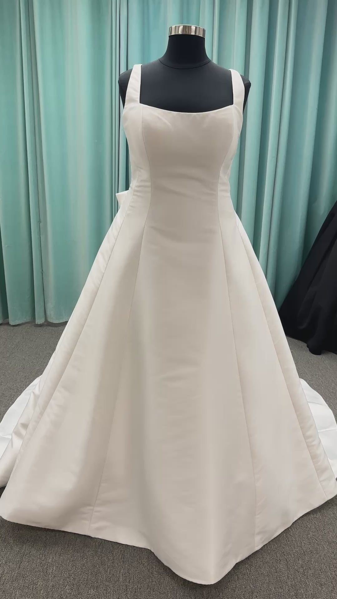 Minimalist Mikado A-line wedding dress with square neckline, clean seams, subtle side cutouts, and detachable oversized bow at the back