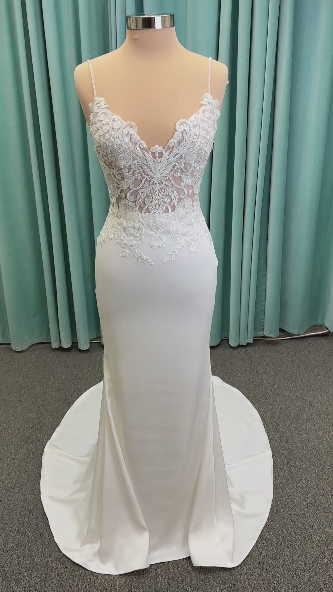 Calliope ivory spaghetti strap V-neck fit-and-flare wedding dress on mannequin with 3D floral lace appliqué bodice and sleek crepe skirt.
