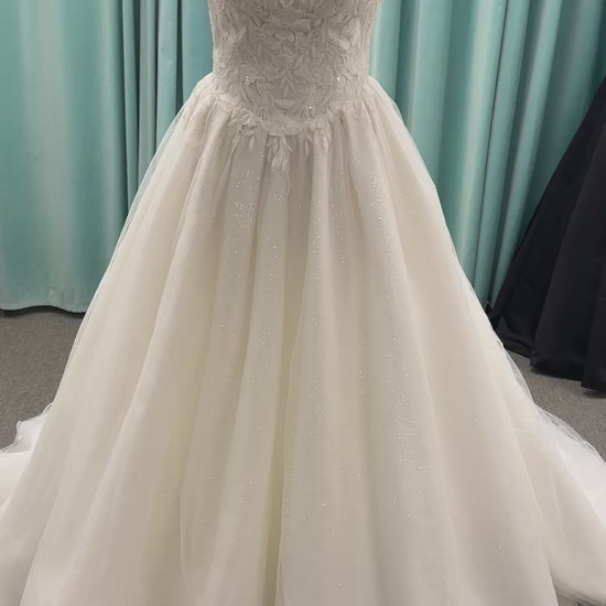 Strapless ballgown wedding dress with sheer boned bodice, sweetheart neckline, and lace appliqués flowing into a full tulle skirt