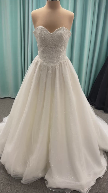 Strapless ballgown wedding dress with sheer boned bodice, sweetheart neckline, and lace appliqués flowing into a full tulle skirt