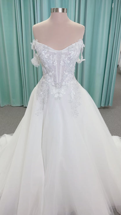Randy Fenoli Indy A-line wedding dress on mannequin with off-the-shoulder sleeve drape, strapless sweetheart bodice, lace appliqué, basque waist, and high skirt slit