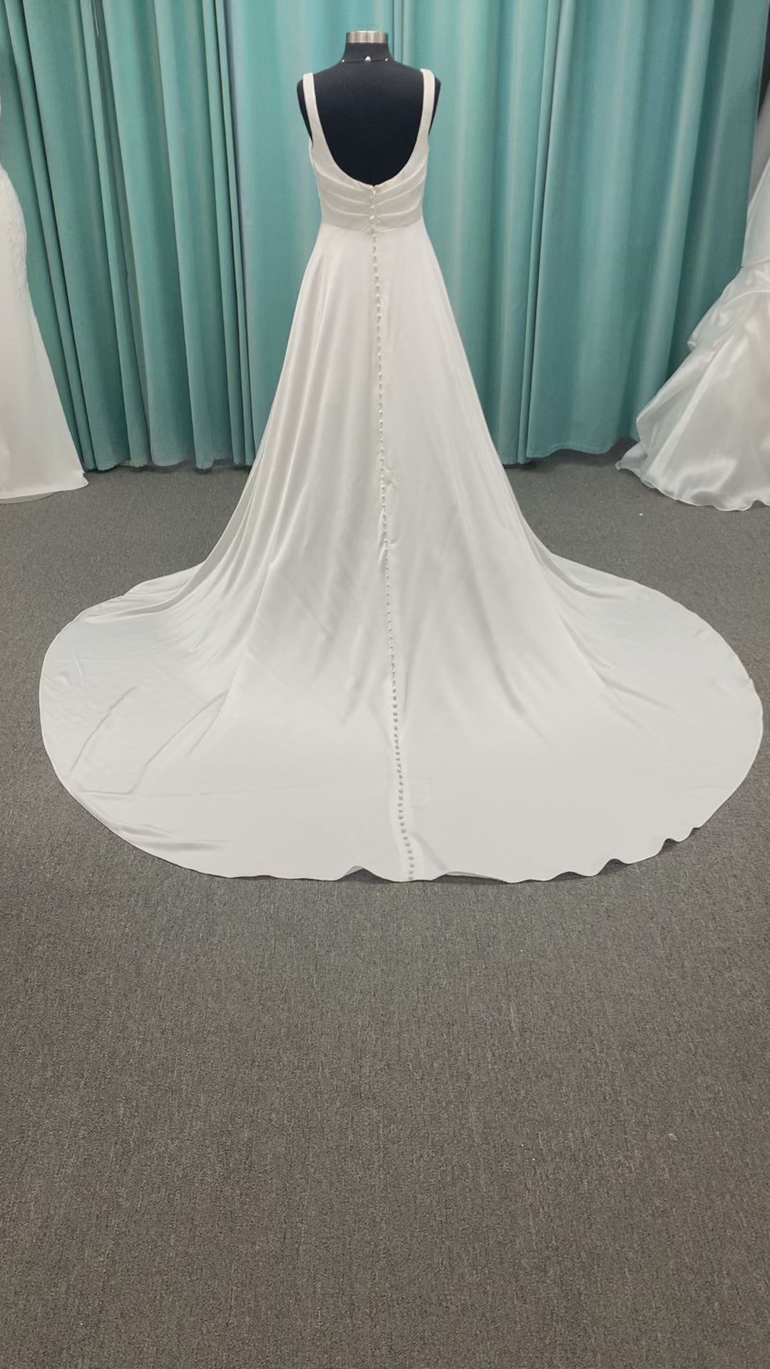 Stella York SY8110 ivory satin A-line wedding dress on mannequin with square neckline, shoulder straps, ruched bodice, and scoop back with fabric-covered buttons.
