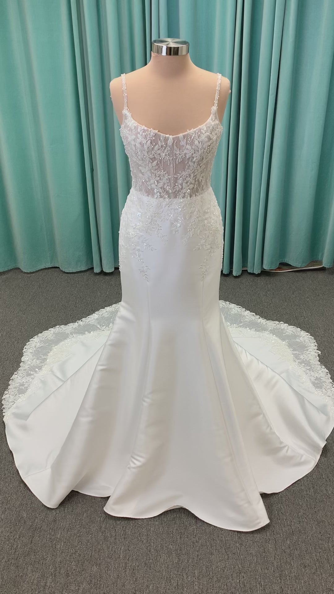 Marjorie ivory spaghetti strap wedding dress on mannequin with illusion corset bodice, floral lace appliqués, and scoop neckline.
