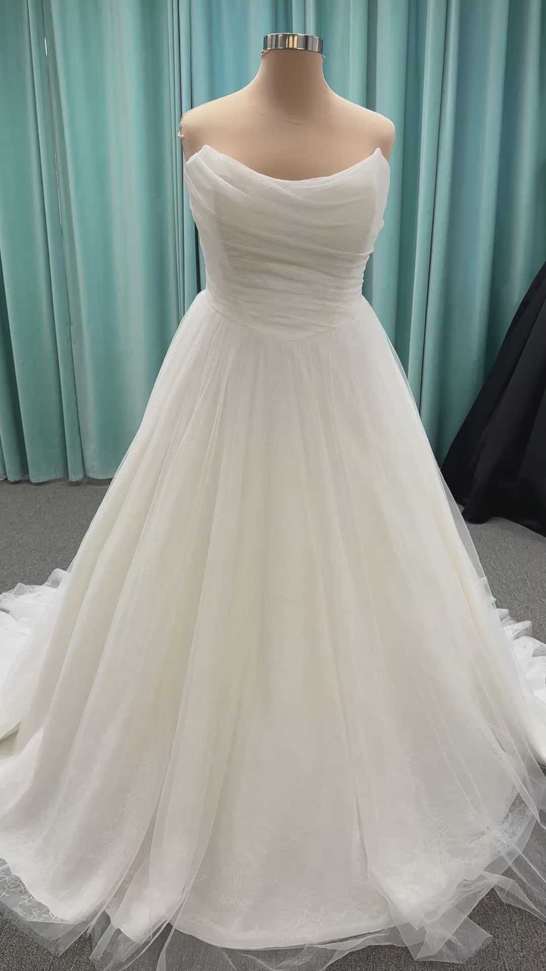 Plus size strapless A-line wedding dress with ruched tulle bodice, Chantilly lace detailing, basque waist, and flowing tulle skirt with train